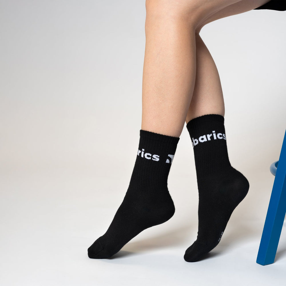 Calcetines barefoot Barebarics Crew negros, puestos, sentada en una silla