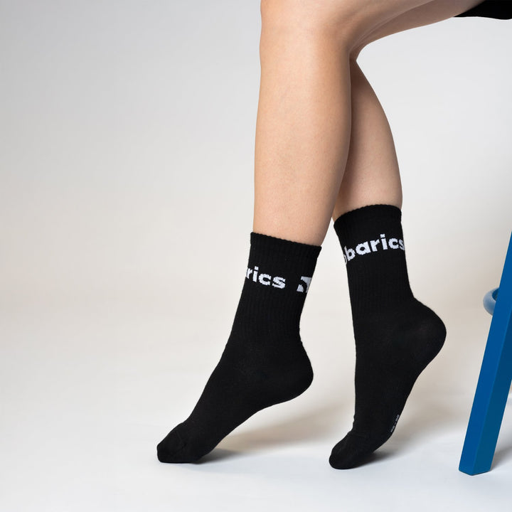 Calcetines barefoot Barebarics Crew negros, puestos, sentada en una silla