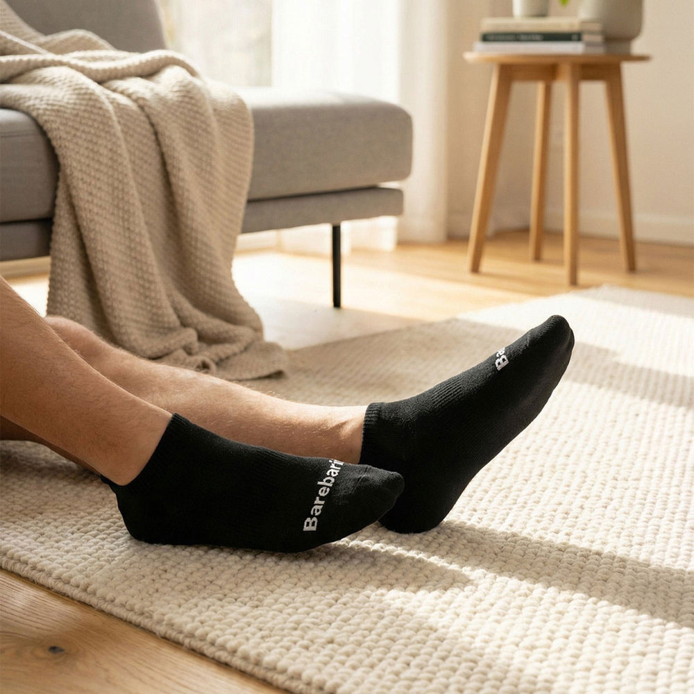 Calcetines barefoot low-cut Barebarics negros, puestos sobre una manta